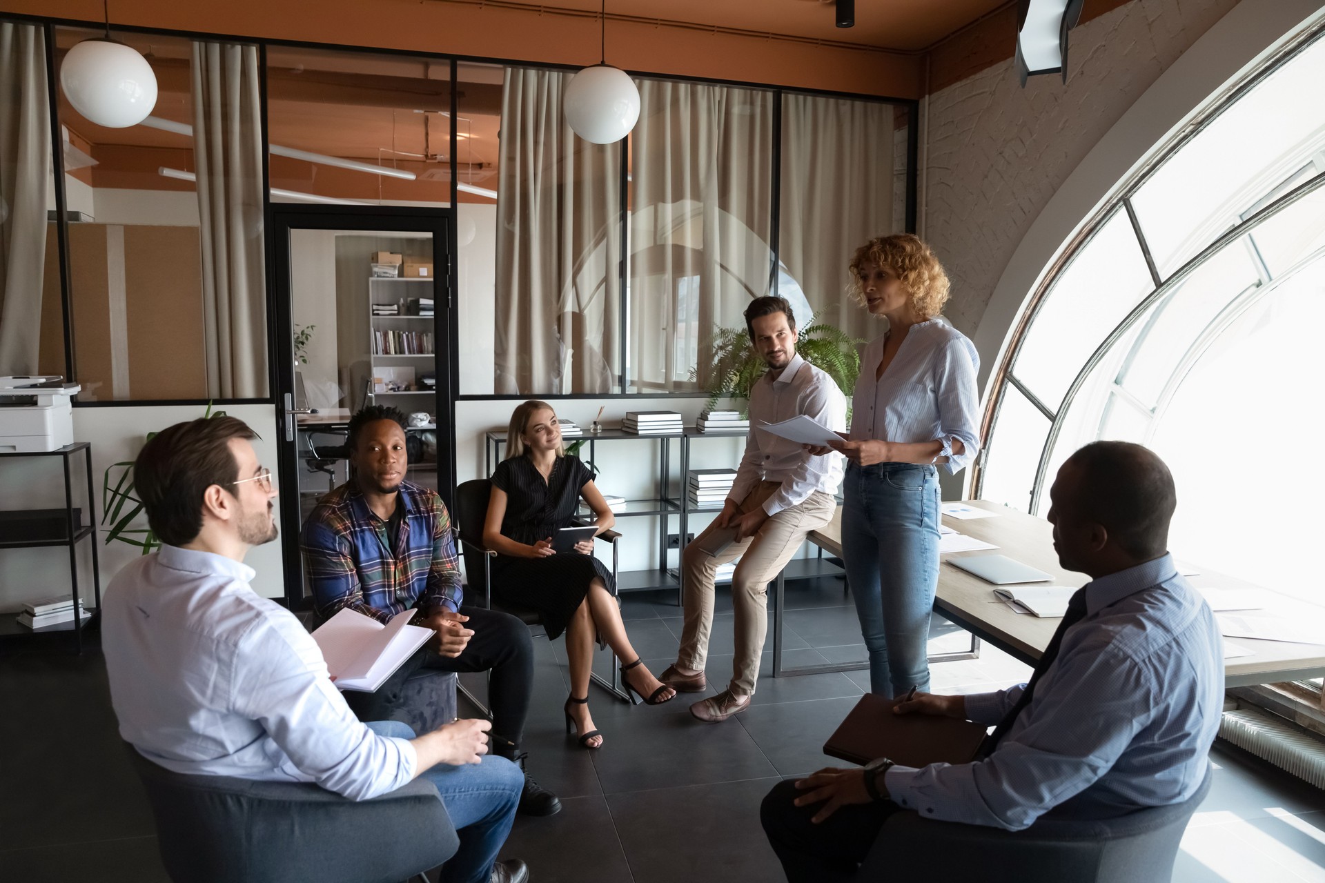 Skilled young female team leader holding meeting with colleagues.
